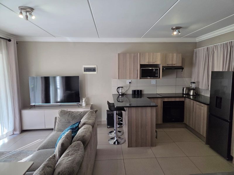Modern open-plan living area featuring a well-appointed kitchen with granite countertops, built-in appliances, and tiled flooring throughout.