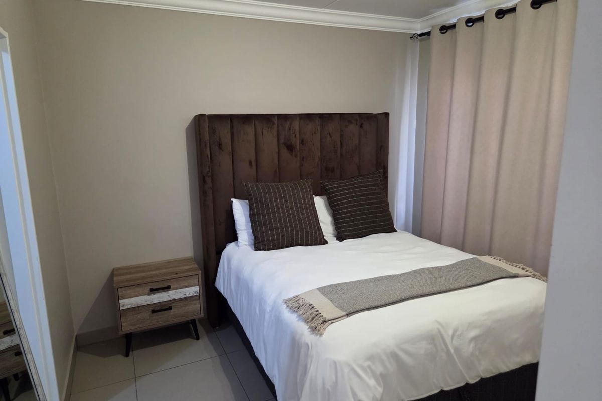 A well-maintained bedroom featuring neutral wall tones, tiled flooring, and classic crown molding, providing a clean and comfortable living space.