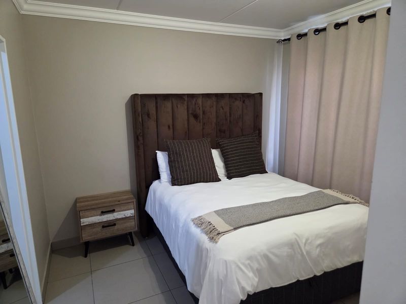 A well-maintained bedroom featuring neutral wall tones, tiled flooring, and classic crown molding, providing a clean and comfortable living space.