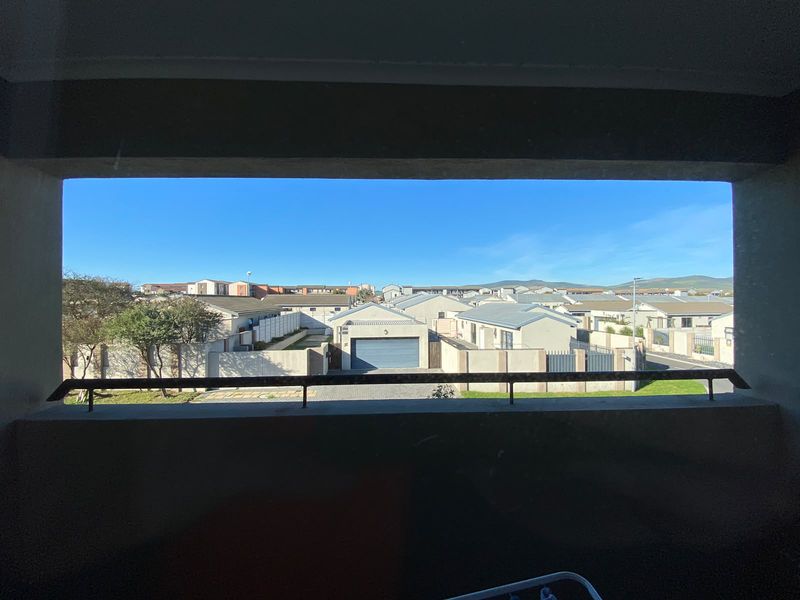 A clear elevated view overlooking a residential neighborhood with surrounding houses and a blue sky.