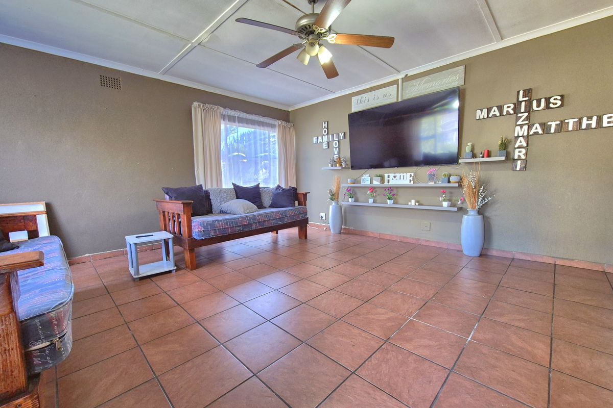 A living room featuring tiled flooring, a ceiling fan, and built-in wall shelving.