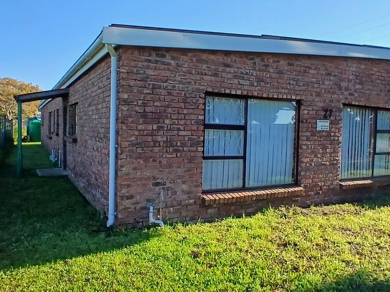 A single-story face brick house featuring aluminium window frames with security bars, set on a grassed plot with a satellite dish installed.