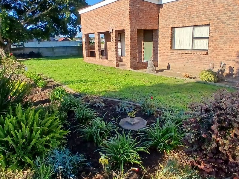 Front view of a face-brick house featuring a well-maintained garden and established landscaping.