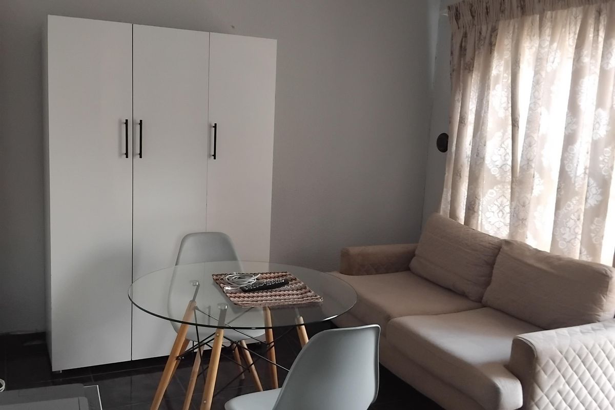 A living area featuring dark tiled flooring and a built-in white wardrobe, providing a functional space with neutral wall tones.