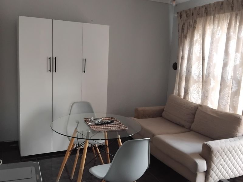 A living area featuring dark tiled flooring and a built-in white wardrobe, providing a functional space with neutral wall tones.
