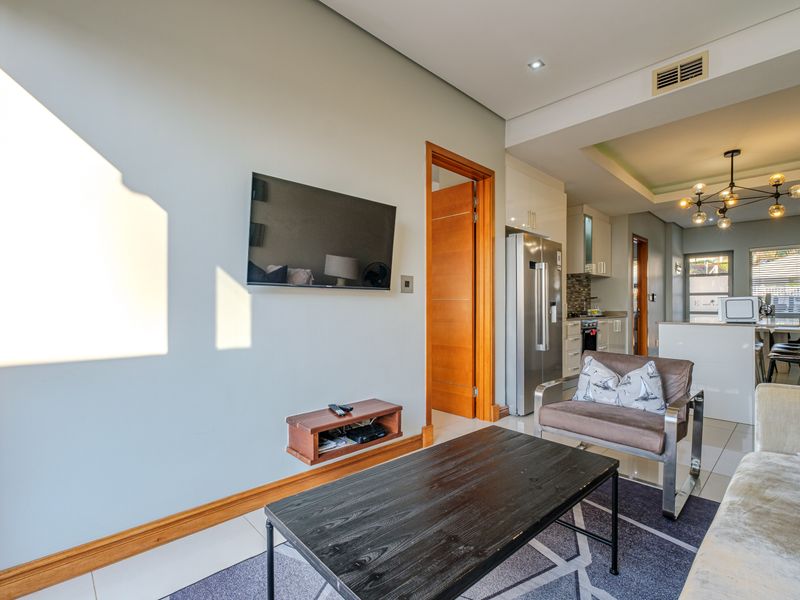 An open-plan living and kitchen area featuring tiled floors, recessed lighting, ducted air conditioning, and modern kitchen cabinetry with a central island.