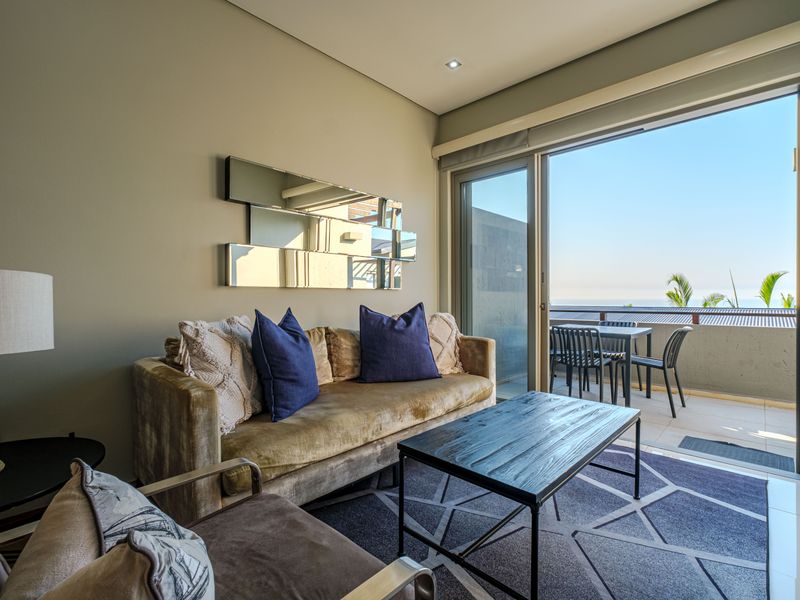 A well-maintained living room featuring large sliding glass doors that open onto a balcony with ocean views.