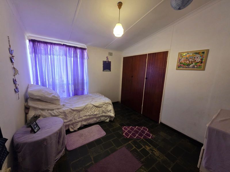A bedroom featuring built-in wooden wardrobes, stone tile flooring, and a pendant light fixture.