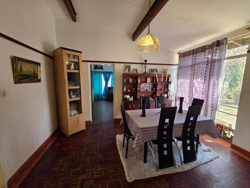 Dining room featuring classic parquet flooring, exposed timber ceiling beams, and a picture rail, with direct access to an adjacent room.