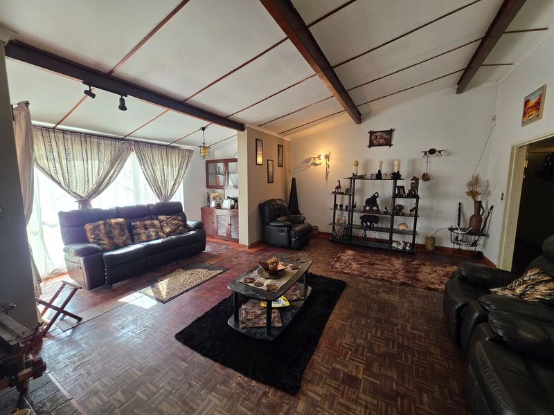 Spacious living room featuring exposed timber ceiling beams and traditional parquet flooring, offering a warm and character-filled foundation for modern updates.