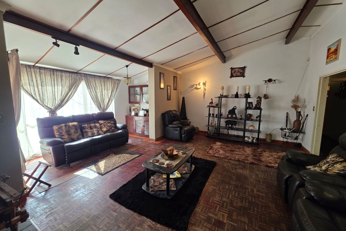 Spacious living room featuring exposed timber ceiling beams and traditional parquet flooring, offering a warm and character-filled foundation for modern updates.