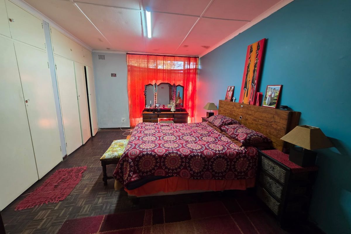 Spacious bedroom featuring built-in cupboards, parquet flooring, and ceiling tiles, offering a functional layout ready for cosmetic updates.