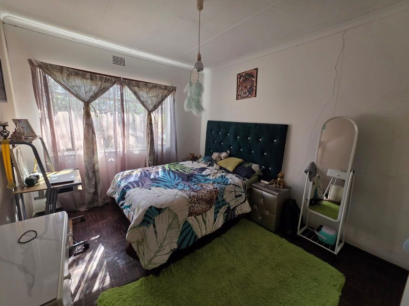 A bedroom featuring parquet flooring and a prominent vertical wall crack requiring repair.