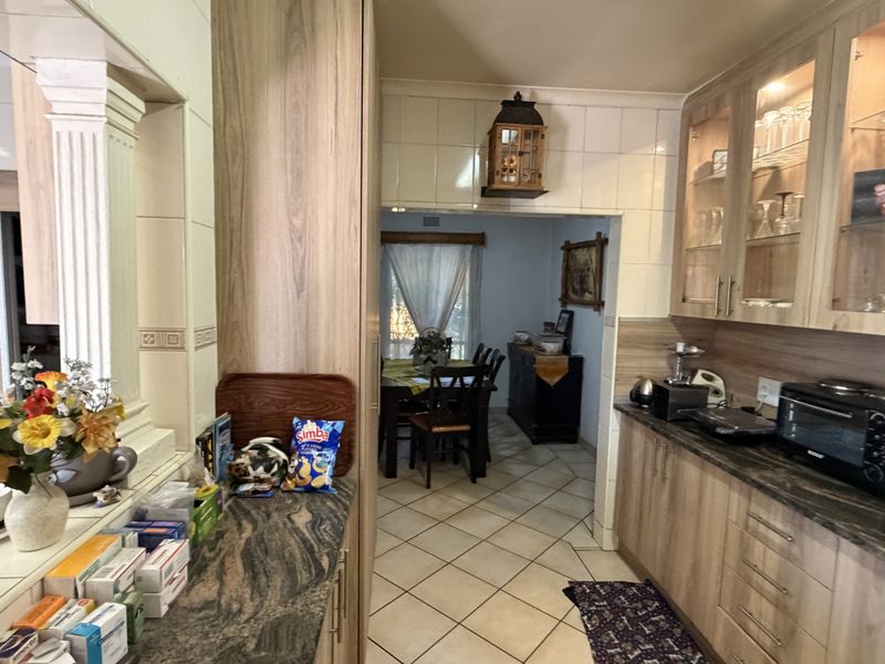 A functional kitchen featuring laminate cabinetry, granite countertops, and tiled flooring, with an open transition leading into the adjacent dining area.