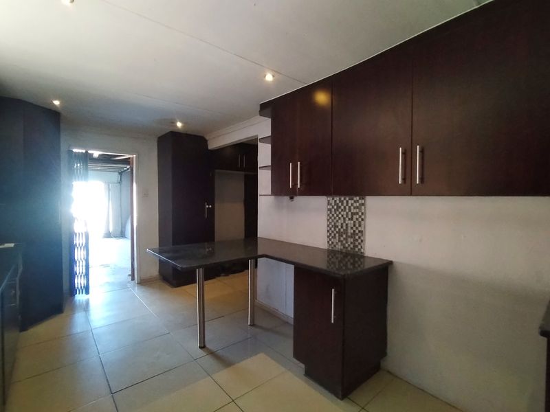 A functional kitchen featuring dark wood cabinetry, granite countertops, and tiled flooring, offering a clean canvas for potential updates.