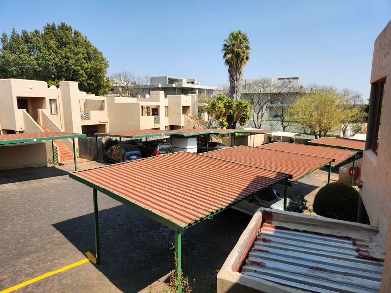 An elevated view of the apartment complex parking area featuring multiple covered carports and paved driveway access.