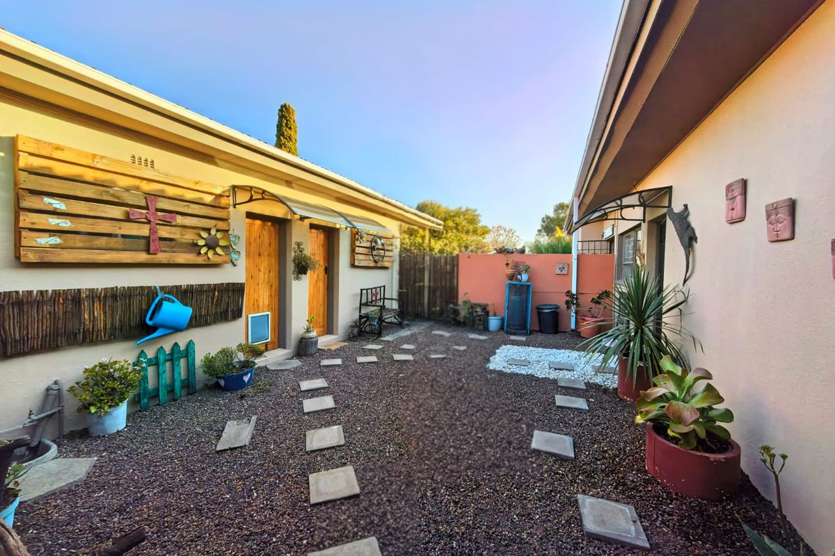 A private rear courtyard featuring a gravel surface, paver stepping stones, and covered access points to the main dwelling.