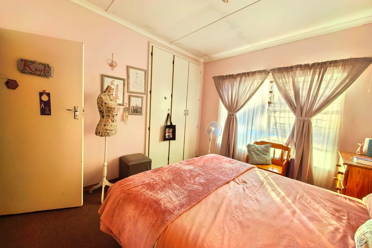 A standard bedroom featuring built-in cupboards and natural light through a window with curtain rails.