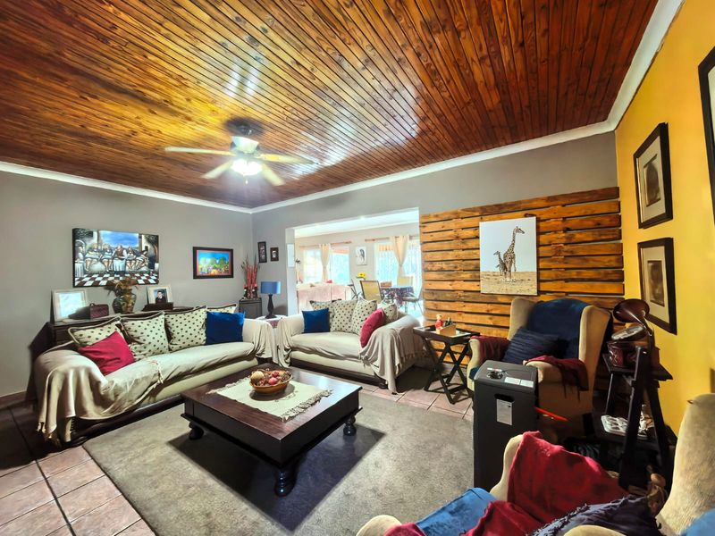 Spacious living room featuring a warm timber-clad ceiling, ceiling fan, and a decorative timber feature wall with tiled flooring throughout.