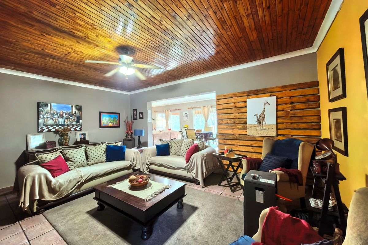 Spacious living room featuring a warm timber-clad ceiling, ceiling fan, and a decorative timber feature wall with tiled flooring throughout.