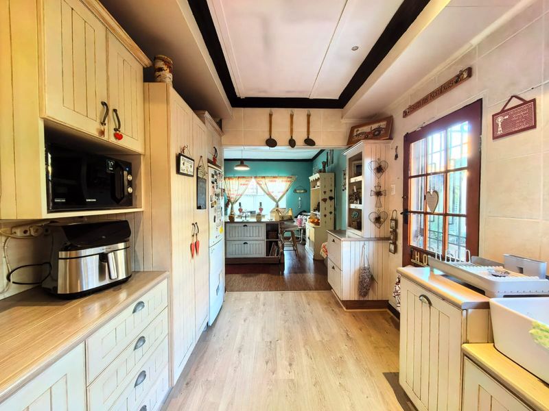 A charming country-style kitchen featuring light-toned built-in cabinetry, wood-look flooring, and a glass-paneled door leading to the exterior.