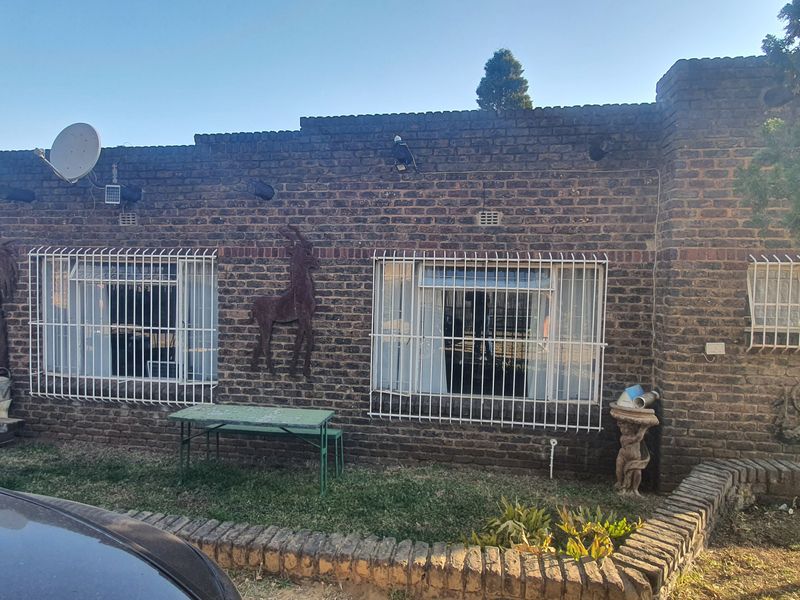 Front elevation of a face brick house featuring security bars on windows and a low brick retaining wall.