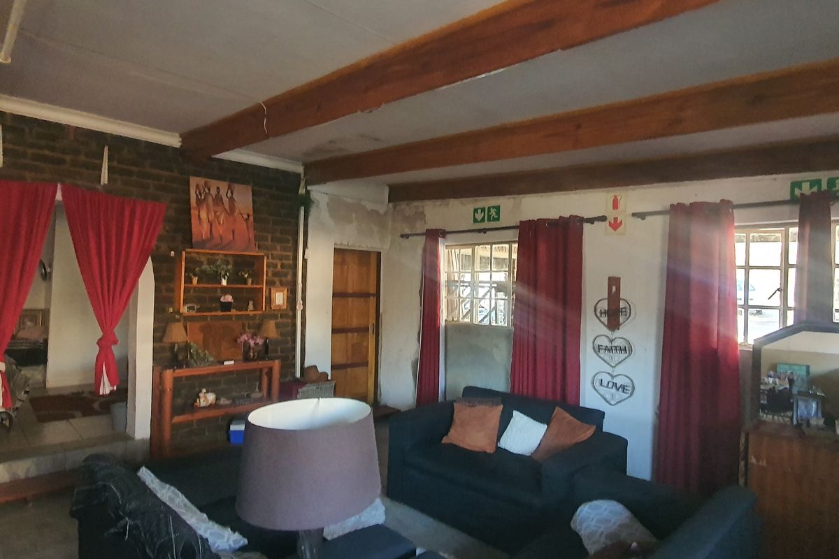 Spacious living area featuring exposed timber ceiling beams and rustic brick wall detailing, offering a character-filled space with potential for cosmetic updates.