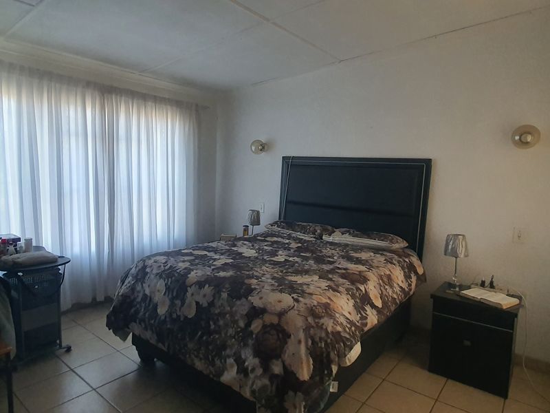 A functional bedroom featuring tiled flooring and wall-mounted lighting, offering a neutral base for personalization.