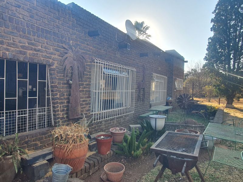 Rear exterior view of the property featuring a face brick facade with installed security bars and a satellite dish.