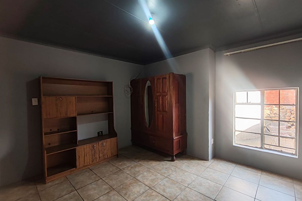 A bedroom featuring tiled flooring and a steel-framed window, requiring cosmetic updates to improve the overall aesthetic and finish.