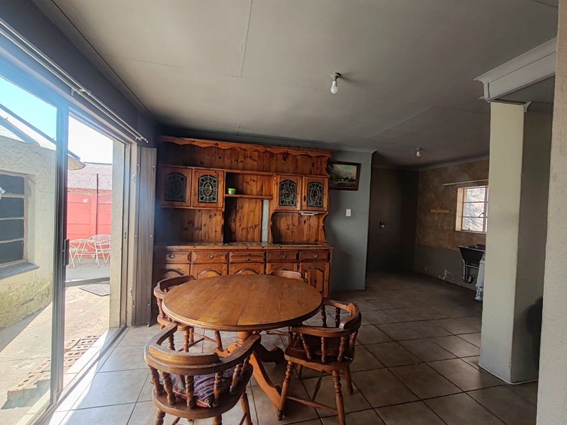 Open-plan living and dining area featuring tiled floors, a sliding door to the exterior, and a built-in wooden cabinet unit.