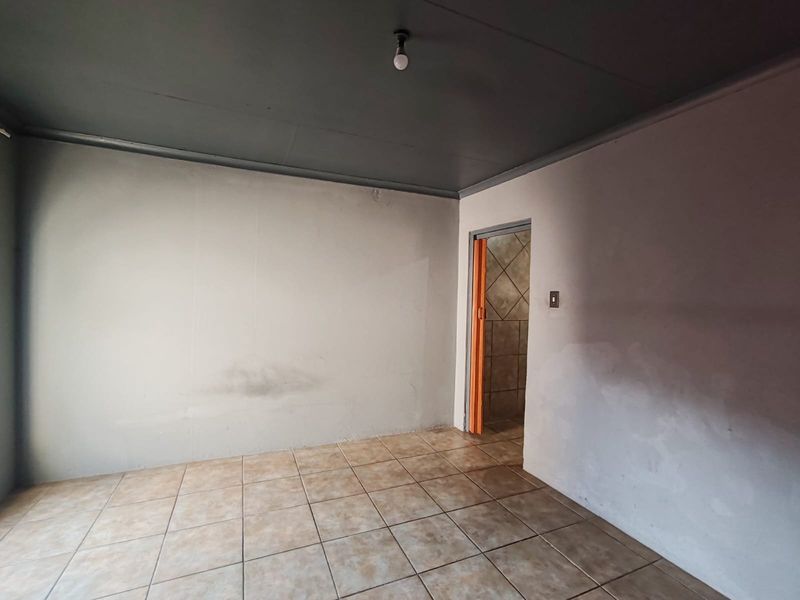 An empty bedroom featuring ceramic floor tiles and a painted ceiling, providing a blank canvas for renovation or interior design updates.