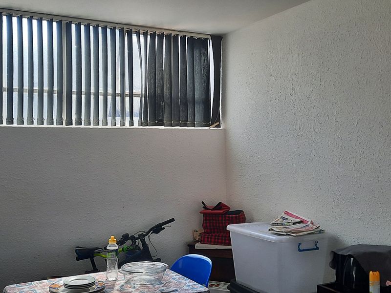 A living area featuring high-level windows with vertical blinds, providing natural light to the space.