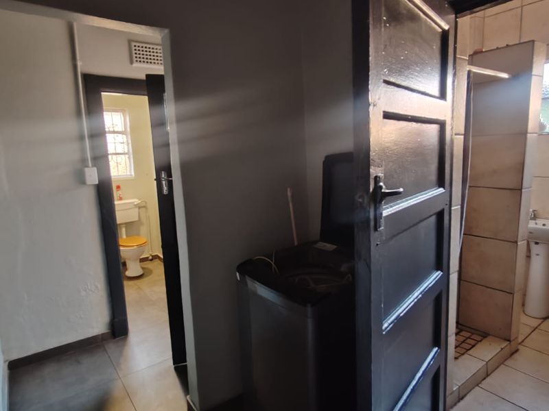 A functional hallway area providing access to the bathroom and toilet, featuring tiled flooring and standard internal door frames.