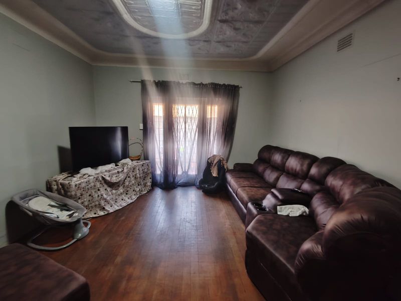 A living room featuring original hardwood flooring, a decorative ceiling, and a sliding door with a security gate leading to the exterior.