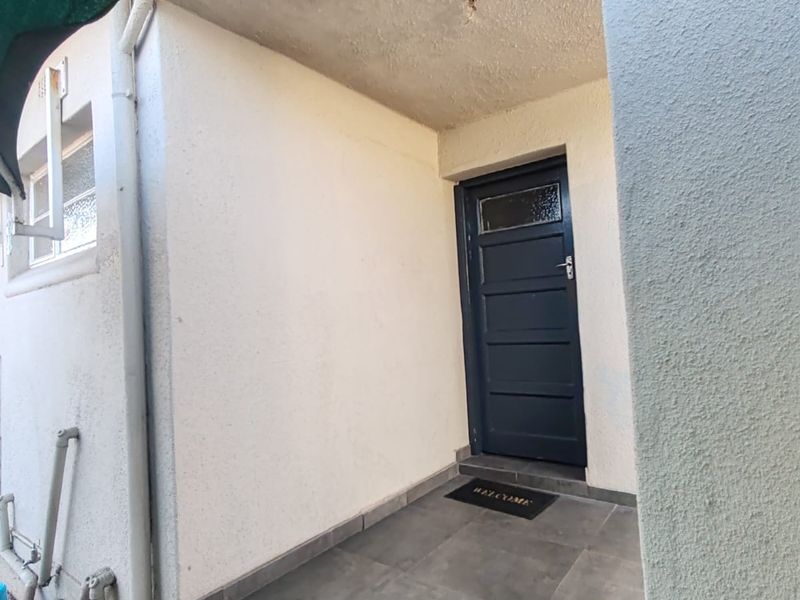 A covered entrance area featuring tiled flooring and a dark-painted exterior door, with some minor ceiling maintenance required.