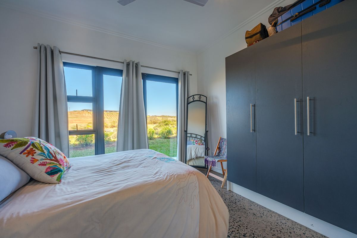 A bright bedroom featuring a large built-in wardrobe, modern flooring, and expansive glass sliding doors providing natural light and scenic views.