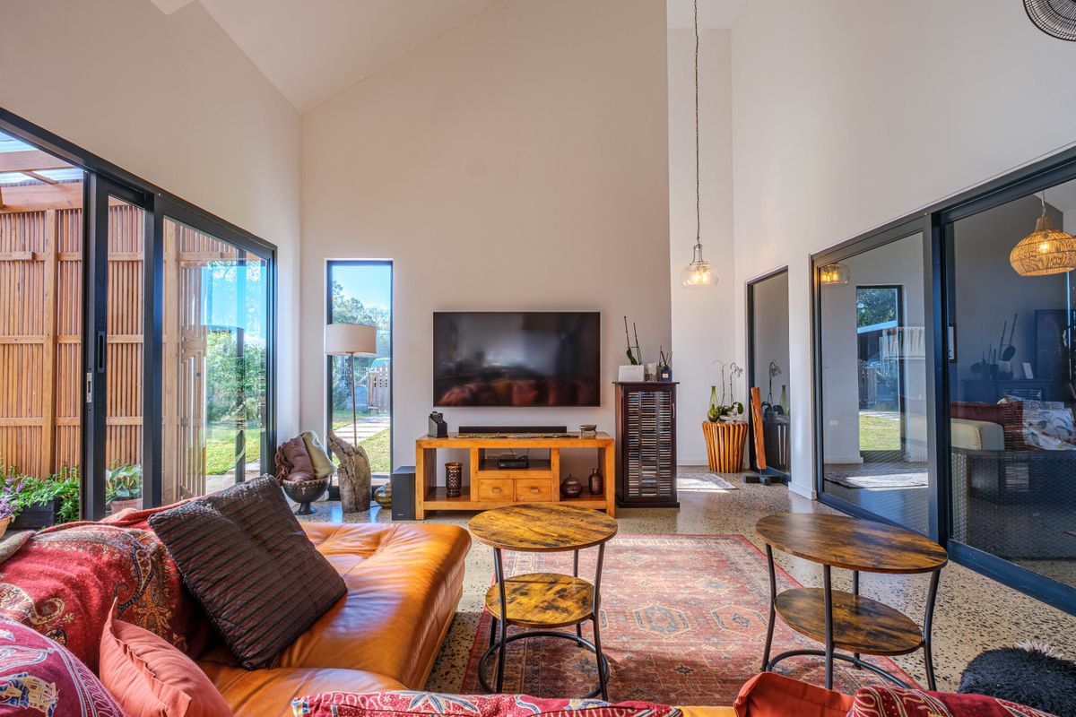 Spacious living room featuring high vaulted ceilings, polished concrete floors, and expansive sliding glass doors that provide abundant natural light and garden access.