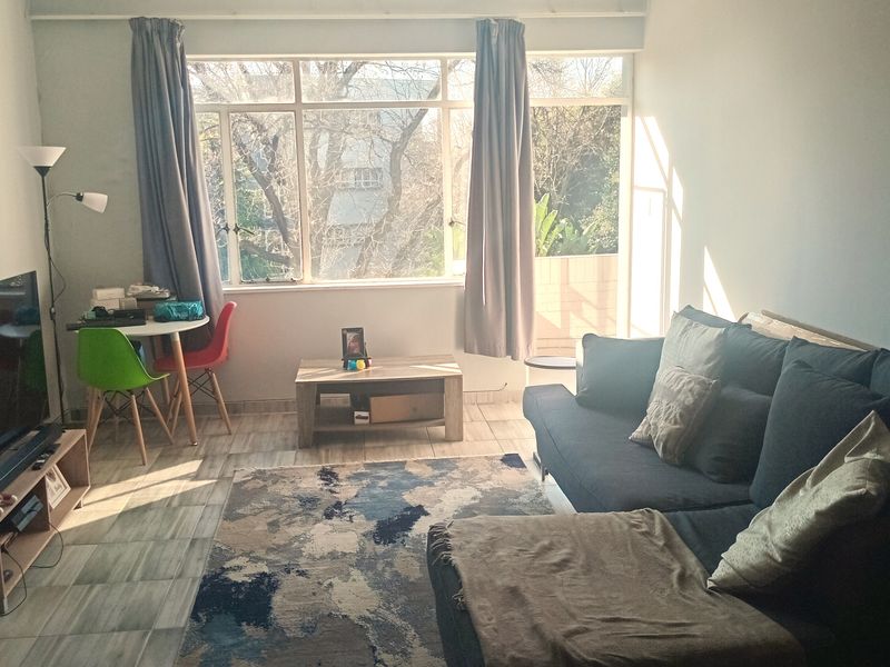 A bright living room featuring tiled flooring and a large window that allows for ample natural light.