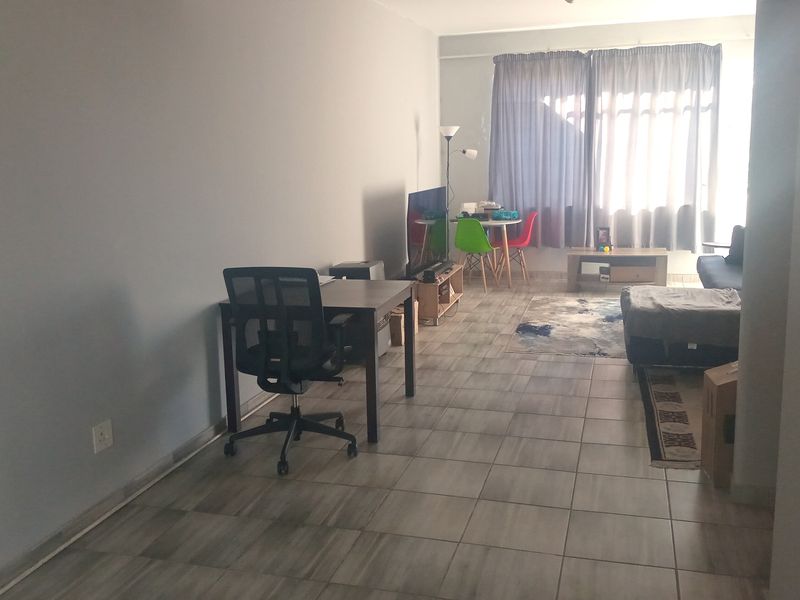 A spacious living area featuring neutral tiled flooring and a large sliding glass door that provides natural light.