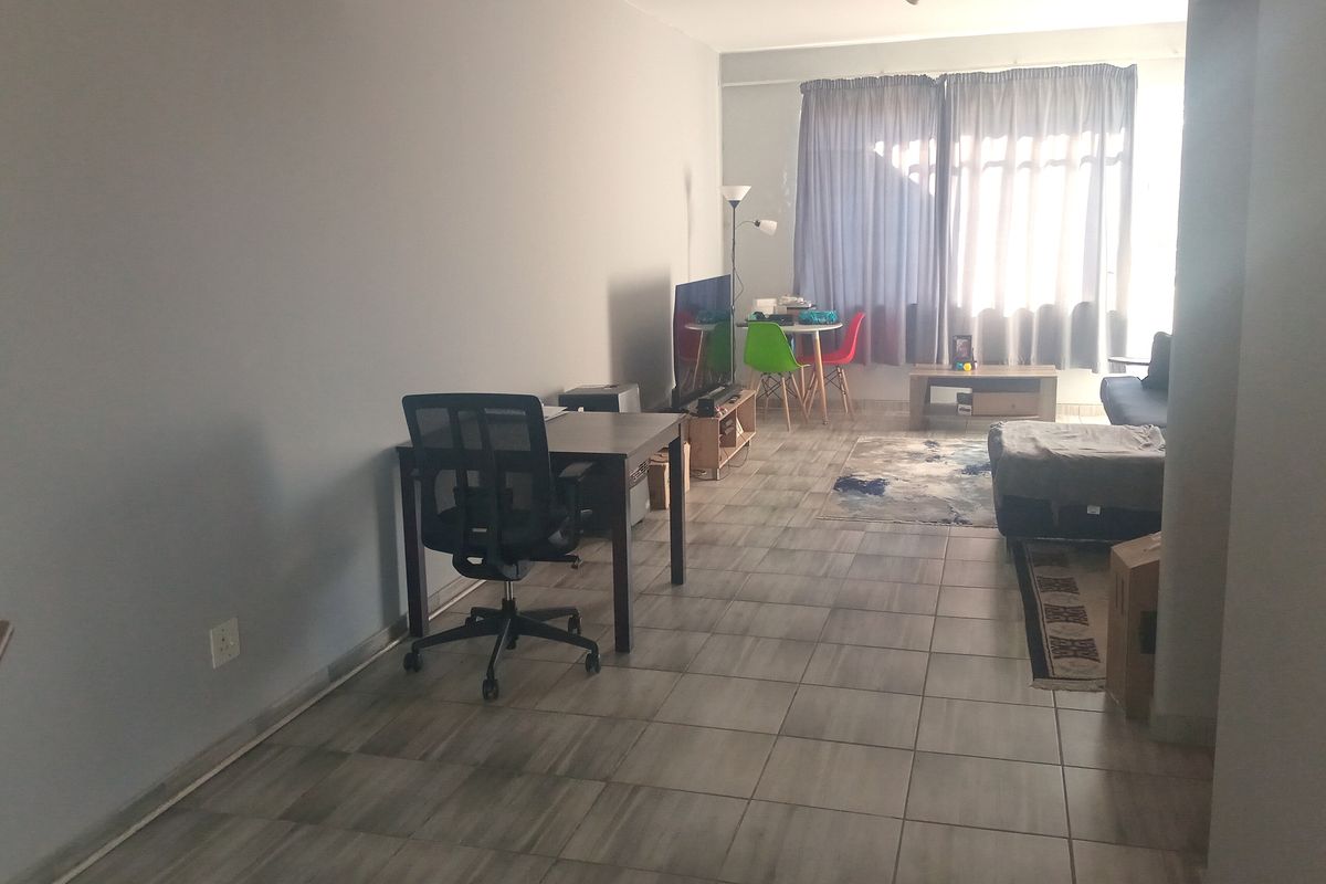 A spacious living area featuring neutral tiled flooring and a large sliding glass door that provides natural light.