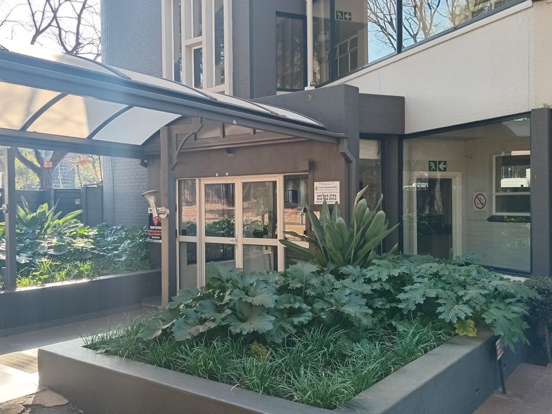 The front entrance of the flat features a covered walkway with a polycarbonate awning, glass doors, and well-maintained raised garden beds.