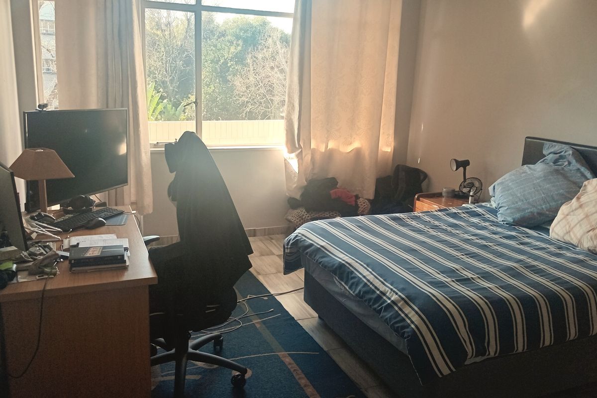 A functional bedroom featuring tiled flooring and a large window that provides natural light.