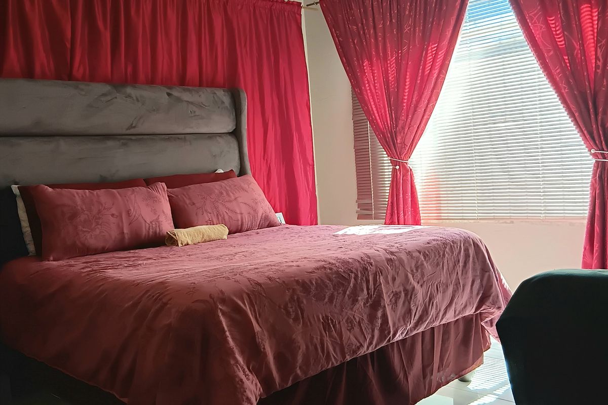 A bedroom featuring tiled flooring, a ceiling fan, and venetian blinds, providing a functional space with natural light.