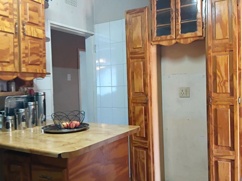 A dated kitchen featuring wooden cabinetry, laminate countertops, and a timber ceiling, offering significant potential for a modern renovation.