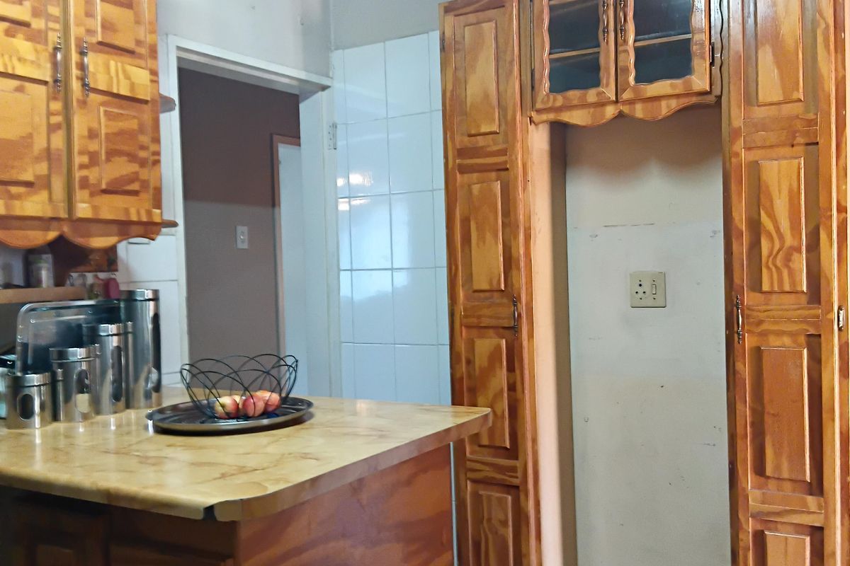 A dated kitchen featuring wooden cabinetry, laminate countertops, and a timber ceiling, offering significant potential for a modern renovation.