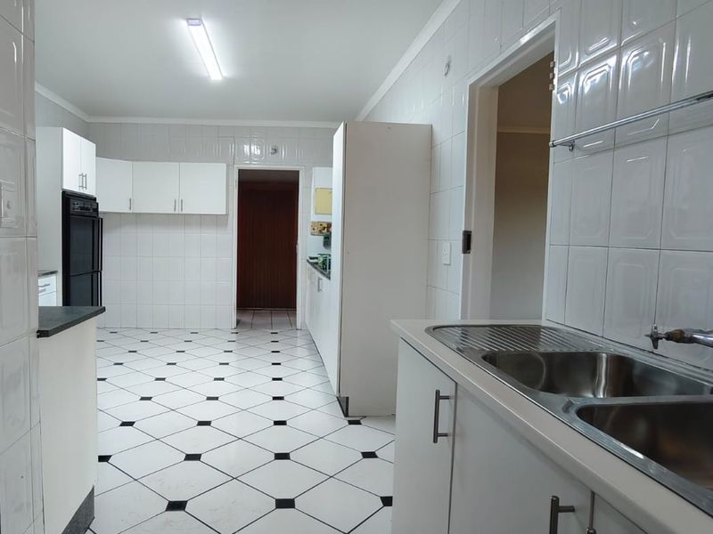 A spacious, functional kitchen featuring white cabinetry, tiled walls, and classic black-and-white patterned floor tiles, offering a clean and neutral foundation for updates.