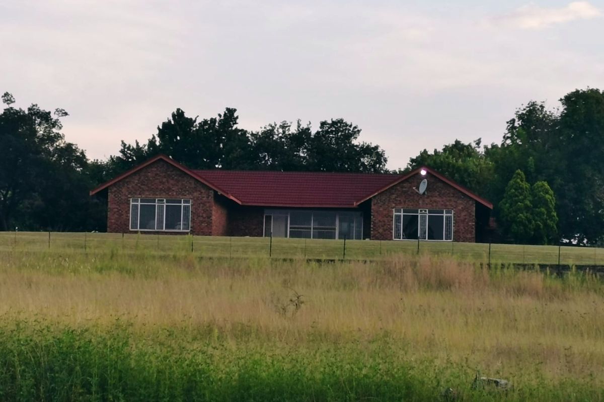 A view of the rear brick facade of the small holding property, featuring a tiled roof and expansive surrounding grounds.