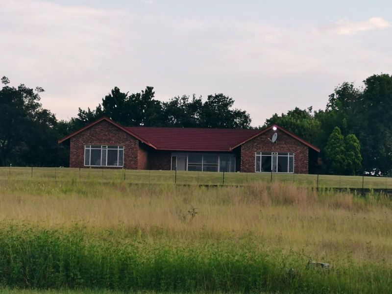 A view of the rear brick facade of the small holding property, featuring a tiled roof and expansive surrounding grounds.
