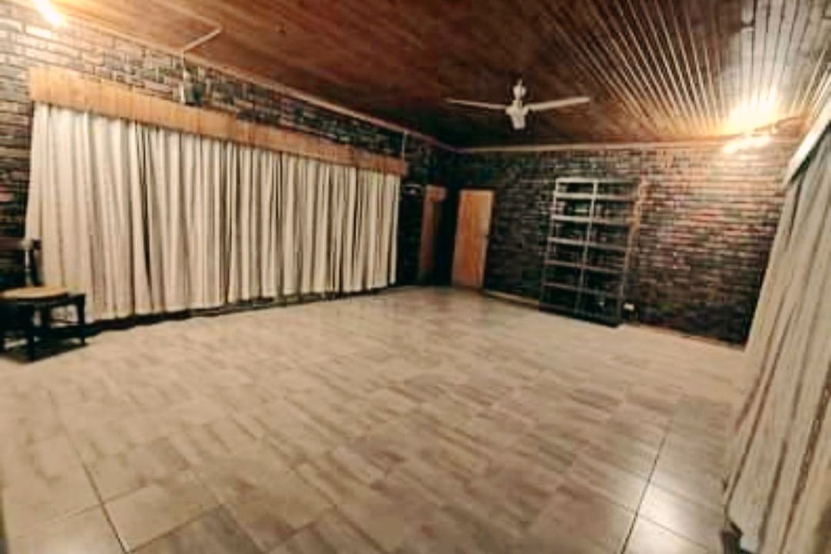Spacious living area featuring rustic exposed brick walls, a warm timber ceiling, and neutral tiled flooring, offering a versatile blank canvas for interior design.